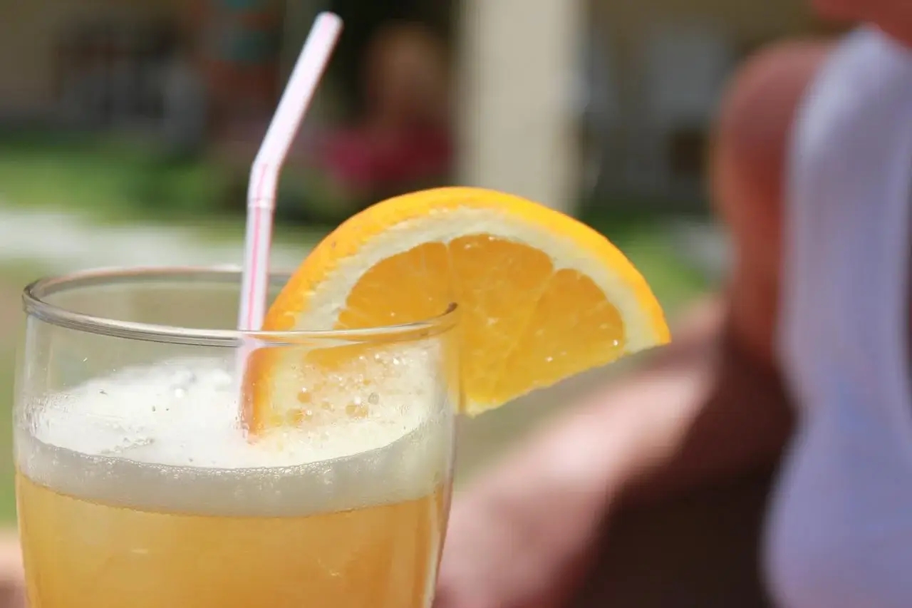Drinki z piwem: shandy w szklance z pomarańczą i słomką