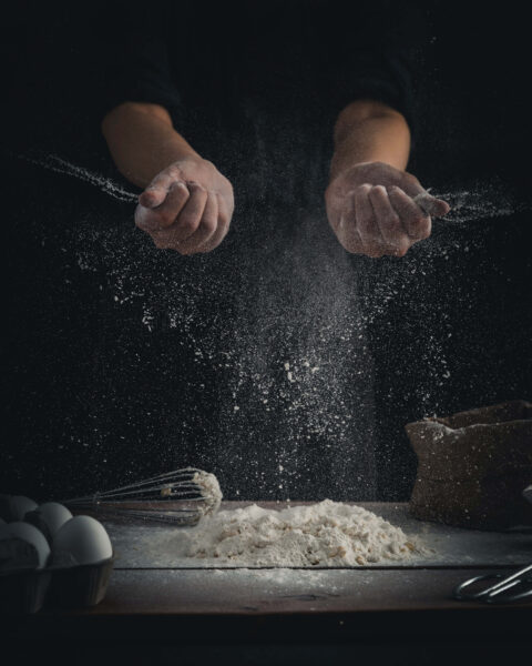 Mężczyzna z wyciągniętymi rękami nad mąką w kuchni