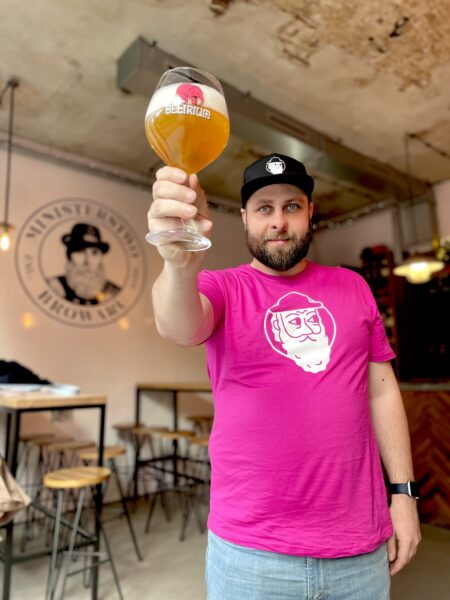 Piotrek, barman z Ministerstwa Browaru, trzymający w ręce piwo.